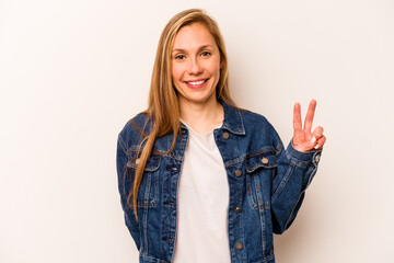 Young caucasian woman isolated on white background showing victory sign and smiling broadly.