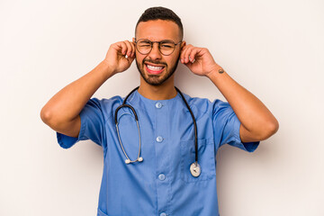 Wall Mural - Young hispanic nurse man isolated on white background covering ears with hands.