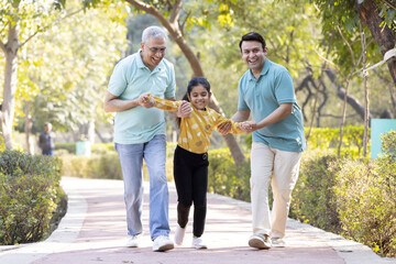 Wall Mural - Cheerful senior man having fun while playing with son and granddaughter at park