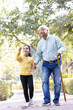 © G-images - Senior man holding stick while walking with granddaughter at park
