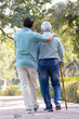 © G-images - Young man helping and supporting his father in walking at park