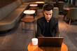 © Ranta Images - Portrait of handsome young businessman using laptop in coffee shop