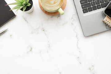 Wall Mural - White marble office desk table with laptop computer, cup of latte coffee and office supplies. Top view with copy space, flat lay.