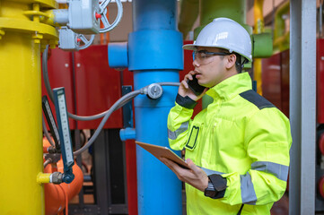 Asian engineer wearing glasses working in the boiler room,maintenance checking technical data of heating system equipment,Thailand people