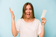Young caucasian woman holding sanitary napkin isolated on blue background receiving a pleasant surprise, excited and raising hands.