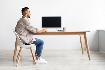 Wall Mural - Arab man using computer with blank empty monitor