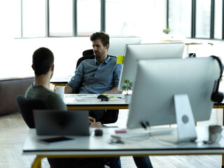Poster - Catching up over coffee. Cropped shot of two businessmen chatting at a desk in their office.