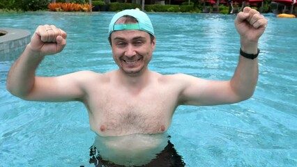 Wall Mural - Happy funny man dancing and having fun in swimming pool excited for summer. Positive excited male traveler enjoying summertime swim on vacation in tropical resort. Slow motion.