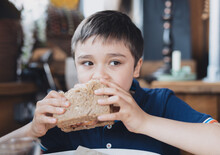 Healthy Kid Boy Eating Homemade Bacon Sandwich With Sliced Wholegrain Bread. Child Having Breakfast In Cafe Or Restaurant. Healthy Life Style Concept