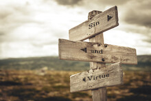 Sin And Virtue Text Quote Written In Wooden Signpost Outdoors In Nature. Moody Theme Feeling.
