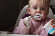 The baby is having lunch. Funny little girl. A one-year-old child eats yogurt on his own
