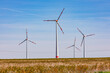 Windräder dominieren eine ländliche Landschaft vor blauem Himmel in Deutschland