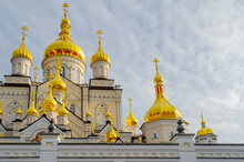 Golden Domes With Crosses Of The Orthodox Christian Religious Building Against The Cloudy Sky. Pochaiv. Ukraine, 2022