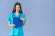 © Eclipsnet - doctor with stethoscope looking at medical report with aquamarine uniform in front on blue background