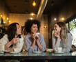 © gonzagon - Group of three multi-ethnic female friends chatting and drinking coffee in a coffee shop