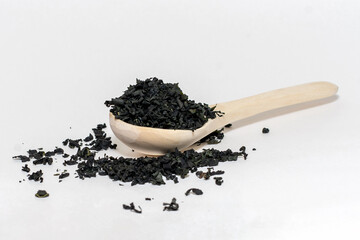 dry wakame algae on a white background on a wooden spoon lie
