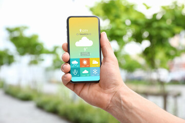 Young man using weather forecast app in his mobile phone, closeup
