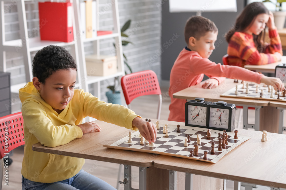Little children playing chess during tournament in club