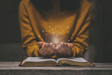 Woman Praying On Holy Bible In The Morning Have A Yellow Lights And Sparkles Coming. Woman Hand With Bible Praying. Christian Life Crisis Prayer To God.