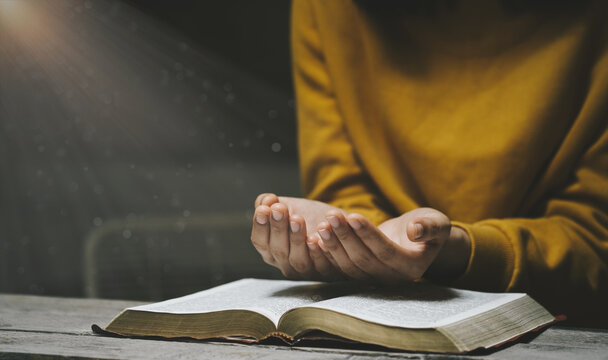 Woman praying on holy bible in the morning have a Yellow lights and sparkles coming. Woman hand with Bible praying. Christian life crisis prayer to god.