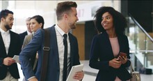 Group Of Diverse Professional Colleagues Talking Walking In Modern Office, Happy Friendly African Female And Caucasian Male Coworker Having Conversation Discuss Project Going Along Business Work Space