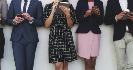 Aufkleber - Making corporate connections. 4k video footage of a group of businesspeople using digital devices while standing against a wall.