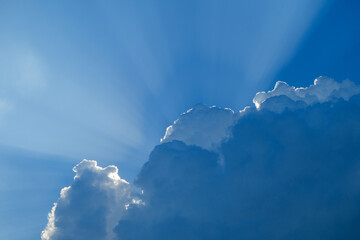 Stunning heavenly light rays from behind the clouds on blue sky