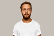 © Anatoliy Karlyuk - Head and shoulders image of brutal handsome pensive Caucasian ginger-head male dressed in white t-shirt with blank copy space for your advertising text, standing over grey wall, looking aside