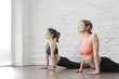 © triocean - Two young women practicing stretching yoga positions in yoga studio. Wellbeing and self care concept.