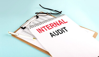 Poster - INTERNAL AUDIT text on notepad on clipboard with chart on blue background, concept closeup. Business and finance concept