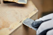 Putty of wood. Manual worker spackling wooden products at the carpentry manufacturing. Close up of working process