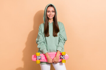 Portrait of attractive cheerful girl holding skate active hobby isolated over beige pastel color background