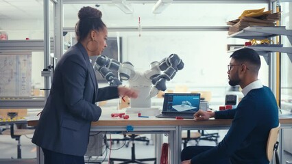 Leinwandbilder - Black Chief Engineer Discussing Futuristic Robotic Arm with Young Promising Computer Scientist Man with Laptop at the Research Laboratory. Innovative Firm Startup Concept. Medium Shot