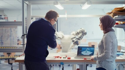 Leinwandbilder - Arabic Female Promising Computer Scientist Asking Her Professor While Discussing Robotic Arm Working to While Gathering at the Table. Innovative Firm Startup Concept. Slow Motion