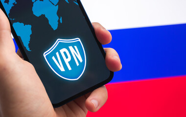 VPN in Russia. Secure and privacy internet. Blocked websites. Hand with mobile phone and VPN application. Flag and laptop on the background