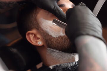 Wall Mural - Professional hairdresser working with bearded client in barbershop, closeup