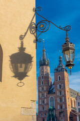 Shadow of a lamp over the Cloth Hall, with St Mary Basilica (out of focus on purpose) in the background in the Market Square of Krakow,  Poland