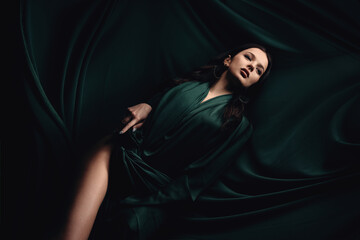 fashionable photo of a beautiful woman with brunette hair in a dark green dress. dress made of fabri