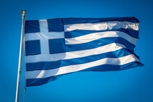 Greek Flag Fluttering In Sunshine Against Blue Sky