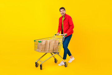 Full size photo of impressed young brunet guy do shopping wear jacket pants shoes isolated on yellow background