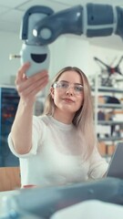 Leinwandbilder - Automation Female Engineer Type at Laptop and Move Bionic Claw At the Factory. Modern Equipment and New Era in Computer Science Industry Concept. Vertical Video
