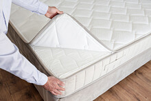 Cropped Shot Of Man Showcasing The Waterproof Topper For White Orthopedic Mattress. Male Showing Hypoallergenic Foam Matress Protector. Close Up, Copy Space, Top View, Background.