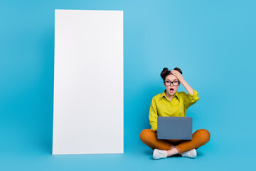 Poster - Full length portrait of impressed confused lady sit floor hand forehead huge phone isolated on blue color background