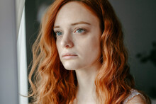 Sad Redhead Woman Looking Out Window In Room