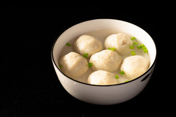 Closeup of six homemade meatballs on the white plate isolated on the black background