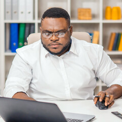 Workplace at home office. Young African-American man works using a computer and other devices. Remote job concept.