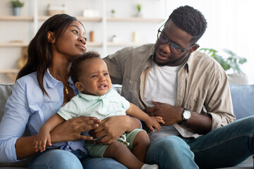 Wall Mural - African American parents comforting crying kid on sofa