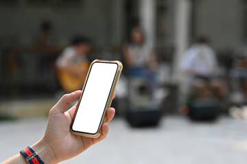 Poster - Close up of a man standing outdoor holding a smartphone with a white blank screen and have people in the background, for business, communication and technology concept.
