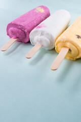 Wall Mural - Vertical closeup shot of different flavored ice creams on a blue background