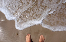 Legs On The Beach And The Sea Foam